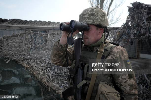 An Ukrainian serviceman patrols at the checkpoint in the village of Shyrokyne near Mariupol, the last large city in eastern Ukraine controlled by...