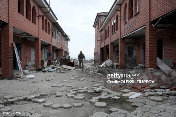 An Ukrainian serviceman walks past destroyed buildings in the village of Shyrokyne near Mariupol, the last large city in eastern Ukraine controlled...