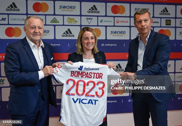 French football coach Sonia Bompastor holds a team jersey as she poses with Olympique Lyonnais' President Jean-Michel Aulas and General director...