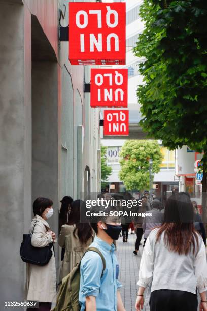 Shoppers wearing masks walk in front of a Uniqlo's newly launched shop in Ginza, Tokyo. Fast Retailing Co., operator of the clothing stores, will...