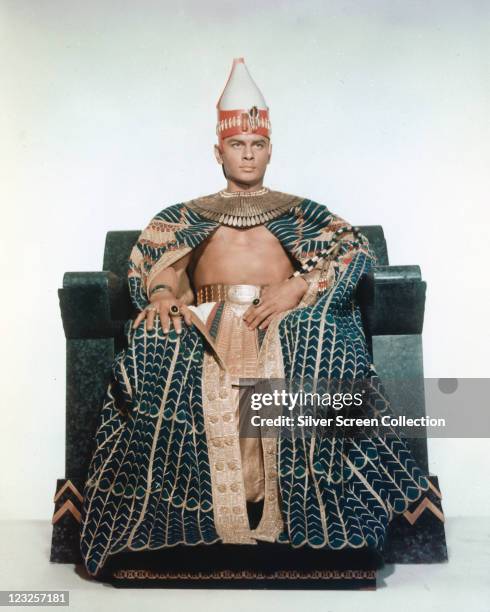 Yul Brynner , Russian-born US actor, in costume sitting on a throne in a publicity portrait issued for the film, 'The Ten Commandments', 1956. The...