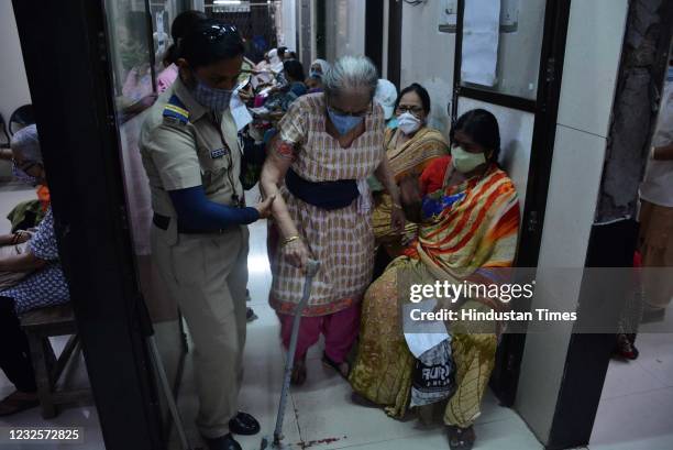 Senior citizen is helped by a lady police officer to take Covid-19 vaccine at Thane Civil Hospital, in Thane, on April 27, 2021 in Mumbai, India.