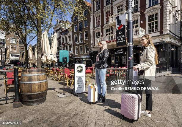 Customers wait to sit on a terrace on the Leidseplein in Amsterdam, on April 28, 2021. - Cafes and bars reopen on April 28 to serve customers outside...