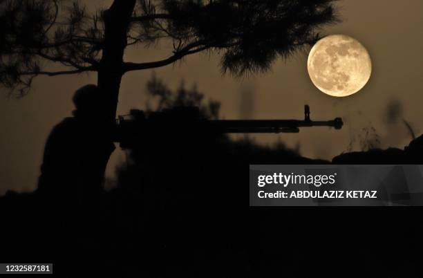 April's Pink Super Moon rises behind a fighter of the Turkish-backed Free Syrian Army in the rebel-held southern countryside of Syria's northwestern...