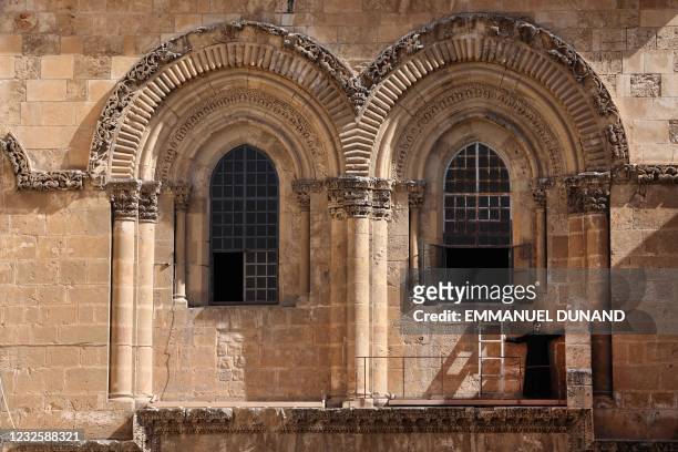 An Armenian Apostolic priest guards the "Immovable Ladder" under one of the windows of the church of the Holy Sepulchre, while the Greek Orthodox...
