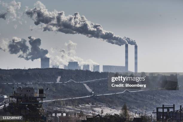 Vapor rises from chimneys and cooling towers at the Belchatow coal powered power plant beyond an open cast lignite mine, operated by PGE SA, in...