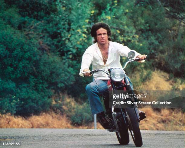 Warren Beatty, US actor, wearing a white shirt as he rides a motorcycle in a publicity still issued for the film, 'Shampoo', 1975. The satire,...