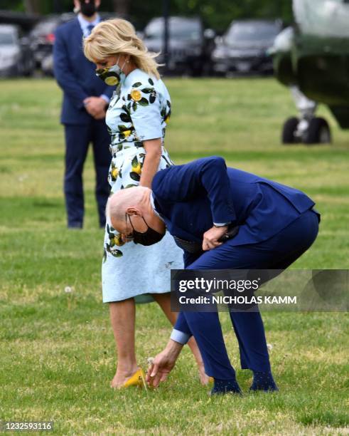 President Joe Biden picks a dandelion flower for First Lady Jill Biden as they depart on Marine One from the Ellipse in Washington, DC, on April 29,...