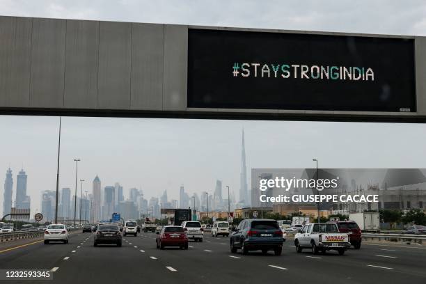 Vehicles drive beneath an electronic billboard bearing the message "#StayStrongIndia" along a highway in Dubai on April 29, 2021. - Indians from the...