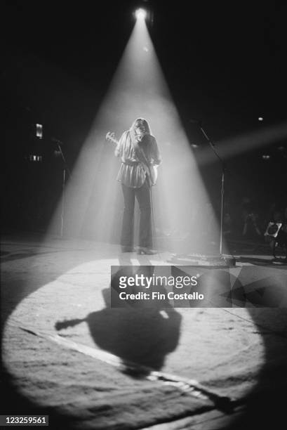 The spotlight lights Geddy Lee, Canadian bassist and guitarist, viewed from behind, casting a shadow across the stage during a live concert...