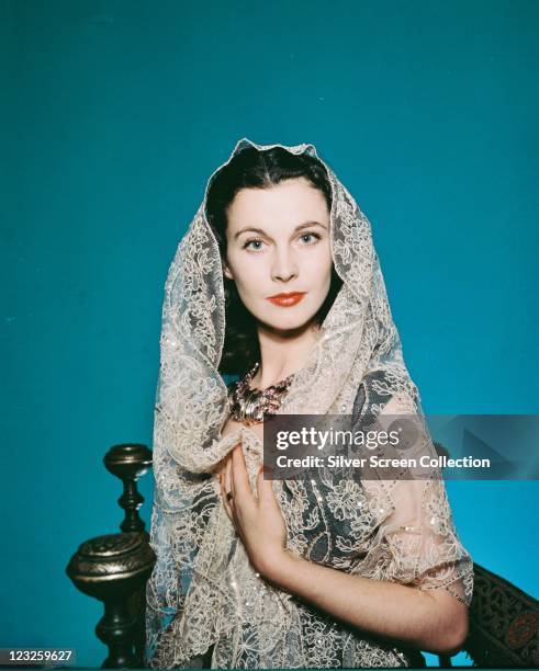 Vivien Leigh , British actress, wearing a white lace veil in a studio portrait, against a blue background, circa 1940.