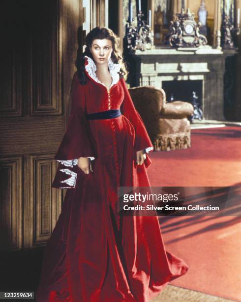 Vivien Leigh , British actress, wearing a long red dress trimmed with white lace, with a black belt, in a publicity portrait issued for the film,...