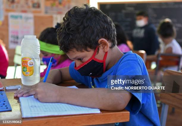 Boy writes on his notebook during a class at an open-air space in Asuncion, on April 29 amid the COVID-19 pandemic. - Since public schools are closed...