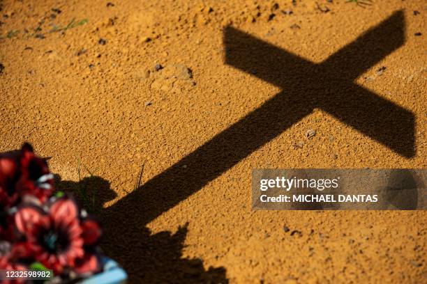 The shadow of a cross from a COVID-19 victim's grave is cast on the ground at the Nossa Senhora Aparecida cemetery in Manaus, Amazonas state, Brazil,...