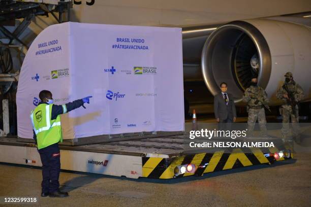 Workers download a container with 1 000 doses of the Pfizer-BioNTech vaccine against COVID-19 from an aircraft upon its landing at the Viracopos...