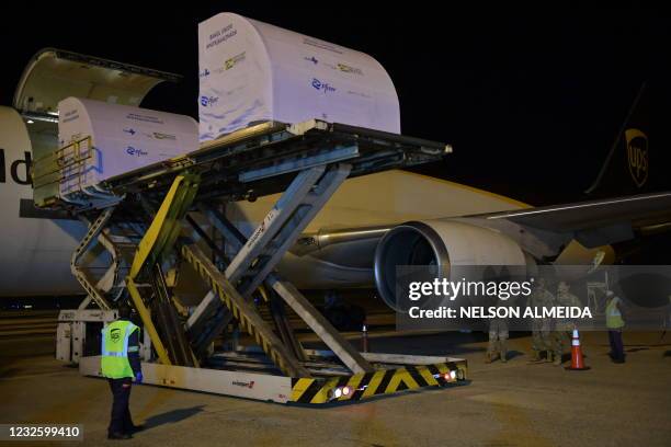 Workers download a container with 1 000 doses of the Pfizer-BioNTech vaccine against COVID-19 from an aircraft upon its landing at the Viracopos...