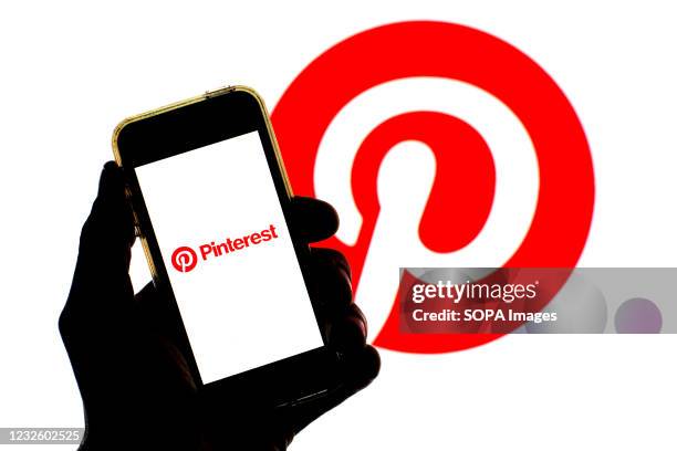 In this photo illustration a Pinterest logo seen displayed on a smartphone screen with a Pinterest logo in the background.