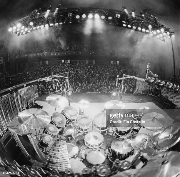 View looking from the back of the stage, looking out over the drumkit on stage and the audience beyond at a concert by Canadian rock band Rush, at...