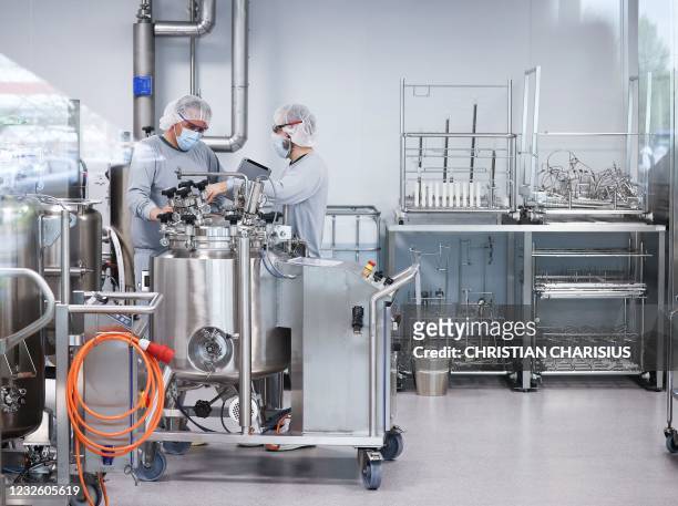 Employees in clean room clothes work on the production of Pfizer/BioNTech's Comirnaty Covid-19 vaccine at the Allergopharma plant in Reinbek near...