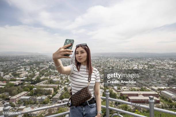 Tourist takes a selfie with the view Osh from Sulaiman-Too Sacred Mountain museum which is visited by many local and foreign tourists every year, in...