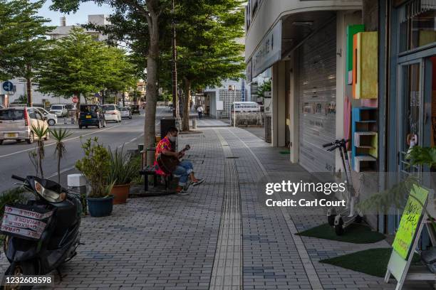 Man plays a guitar on a near-empty street on April 30, 2021 in Miyakojima, Japan. Normally one of Japan's most popular tourist destinations...