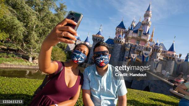 In this handout photo provided by Disneyland Resort, Guests pose in front of Sleeping Beauty Castle at the Disneyland Resort on April 30, 2021 in...