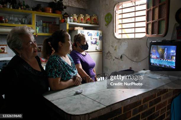 People watch on television the canonisation rite of the Venezuelan saint Jose Gregorio Hernandez transmitted by the Venezuelan public television. San...