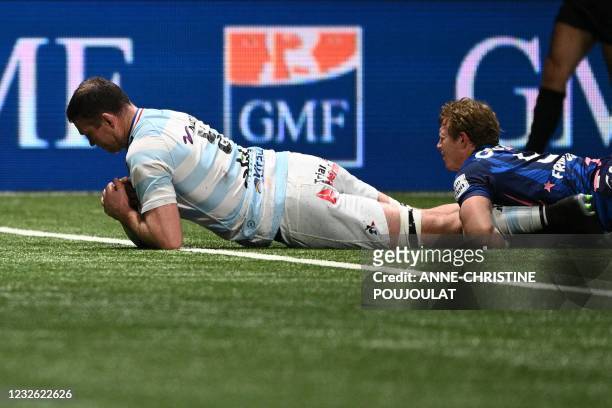 Racing92's Irish lock Donnacha Ryan dives and scores a try as he is tackled by Stade Francais' South African centre James Hall during the French...