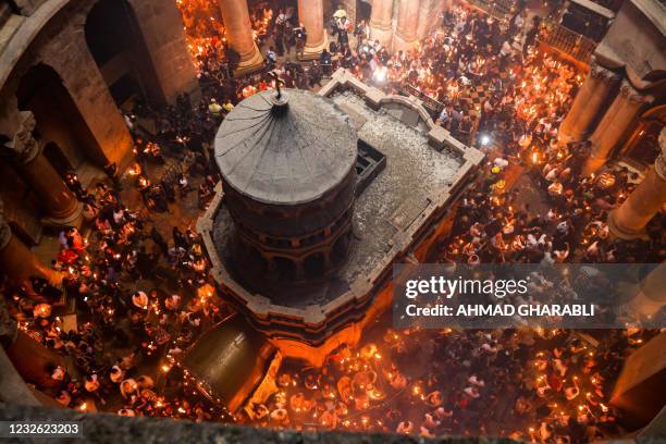 Orthodox Christians gather with lit candles around the Edicule, traditionally believed to be the burial site of Jesus Christ, during the Holy Fire...