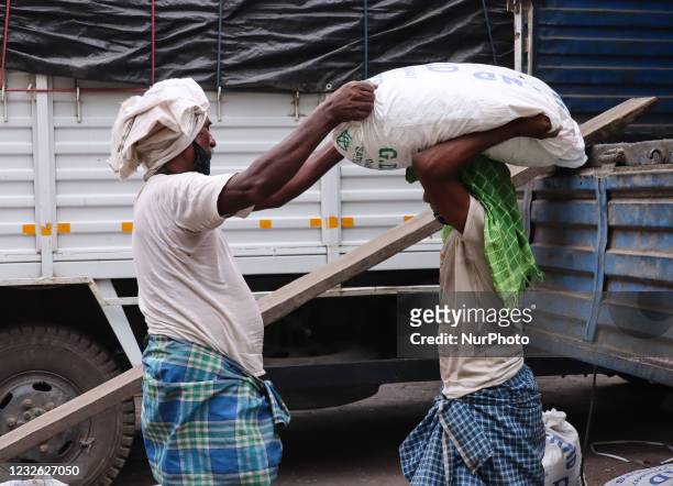 Labourers carry a sack containing grains, during the second wave of coronavirus pandemic in Guwahati, Assam, India on Saturday, May 1, 2021. May 1 is...