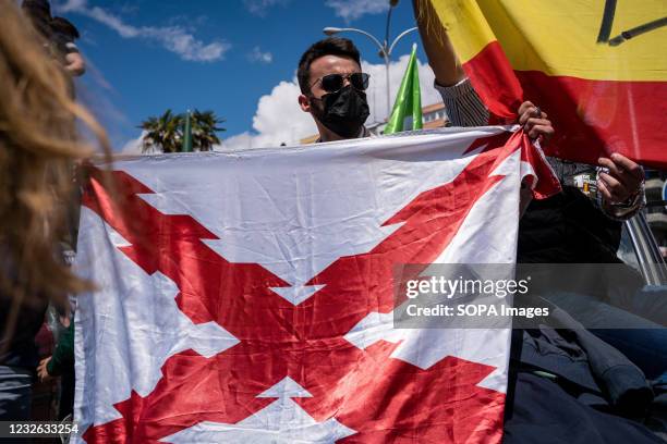 Supporter holds a Carlist flag in Plaza Conde de Casal during the VOX rally. Within the framework of May 1, International Labor Day, the Spanish...