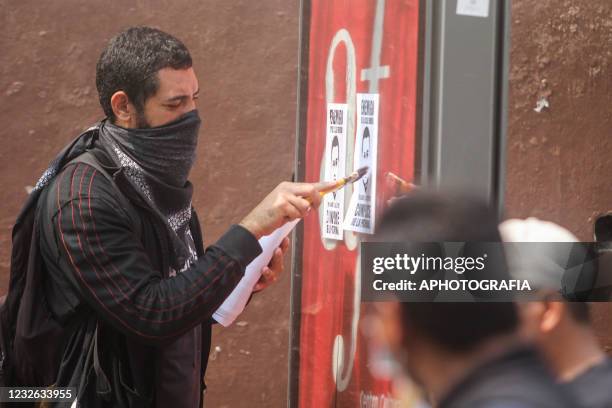 Demonstrator places banners on a wall advocating for unions as part of International Workers' Day on May 1, 2021 in San Salvador, El Salvador. Unions...