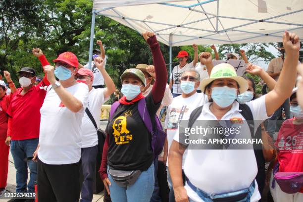 Demonstrators raise their fists as they march as part of International Workers' Day on May 1, 2021 in San Salvador, El Salvador. Unions of both...