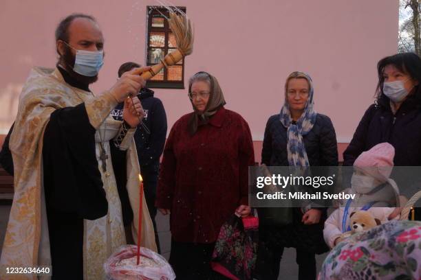 Russian Orthodox Church priest wearing a face mask to protect against the coronavirus blesses painted eggs and cakes prepared for the Orthodox Easter...