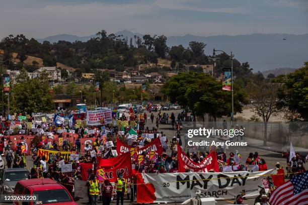 People hold signs in a May Day march from Chinatown to City Hall on May 1, 2021 in Los Angeles, California. May Day dates back to the height of the...