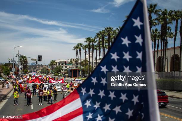 People hold signs in a May Day march from Chinatown to City Hall on May 1, 2021 in Los Angeles, California. May Day dates back to the height of the...