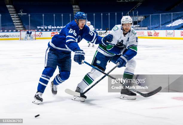 Ilya Mikheyev of the Toronto Maple Leafs battles for the puck against Alexander Edler of the Vancouver Canucks during the first period at the...