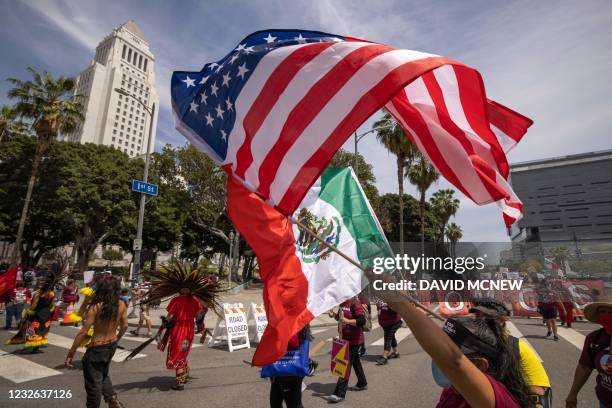 People carry the flags of the United States and Mexico past Los Angeles City Hall as a coalition of activist groups and labor unions participate in a...