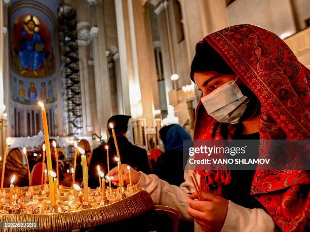 Woman lights a candle during an Orthodox Easter service at Sameba temple church in Tbilisi on May 2, 2021.