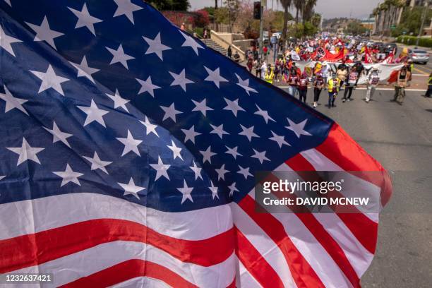 Flag flies overhead as a coalition of activist groups and labor unions participate in a May Day march for workers' and human rights in Los Angeles,...