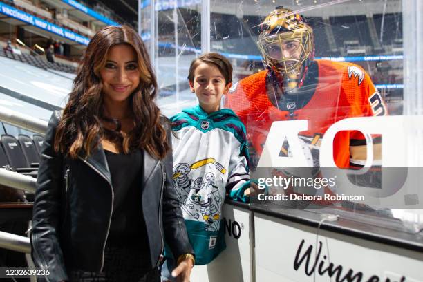 Goaltender Ryan Miller of the Anaheim Ducks poses with his wife Noureen DeWulf, left, and son Bodhi Miller, center during warm-up before the game...