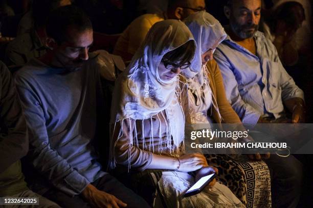 Lebanese Greek Orthodox Christians follow prayers on their mobile telephones during the Easter night mass at the ancient monastery of Our Lady of...