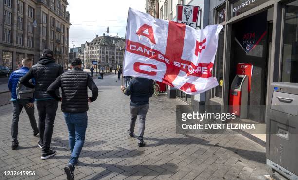 An Ajax supporter carries a large flag of AFCA Supportersclub while walking into the city via the Damrak prior to the Dutch Eredivisie football match...