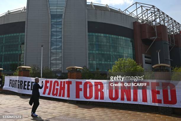 Man takes a photograph of a large banner stating "Fight Greed Fight For United" as supporters prepare to protest against Manchester United's owners,...