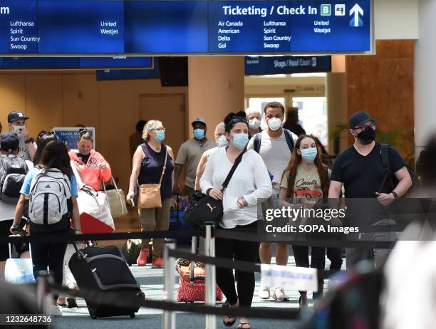 Passengers wearing face masks as a preventive measure against the spread of covid-19 arrive at Orlando International Airport. On April 30 the...