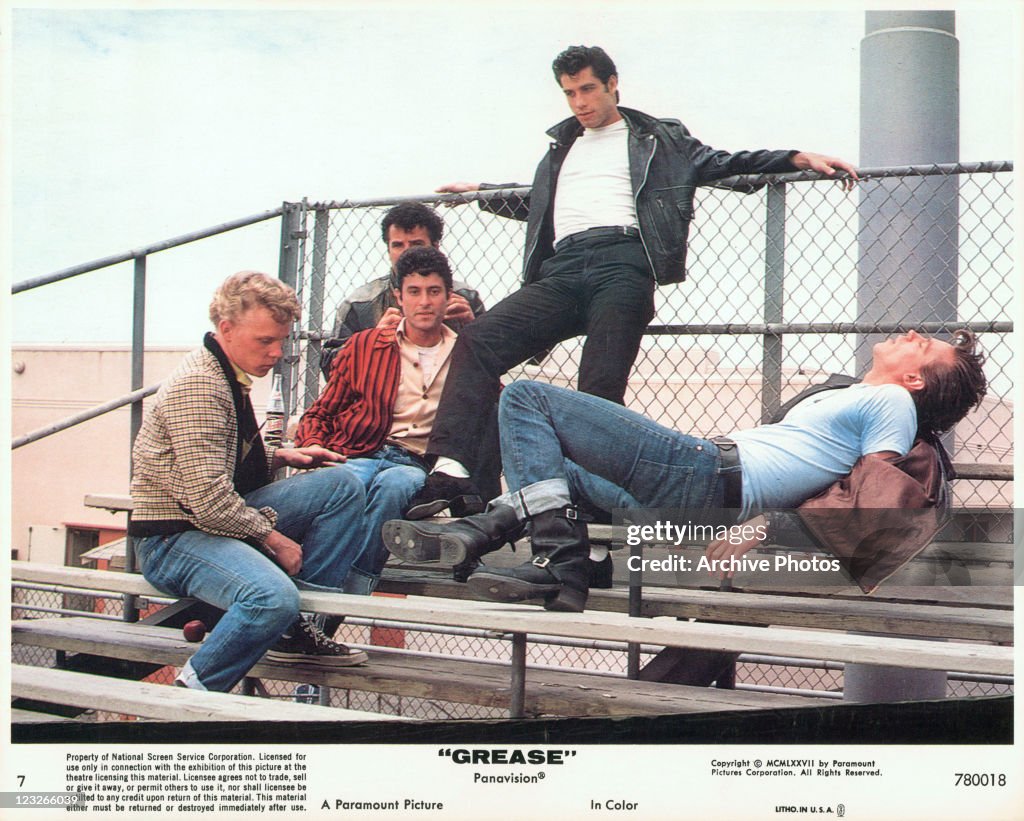 John Travolta hanging out with his crew on the bleachers in a scene ...