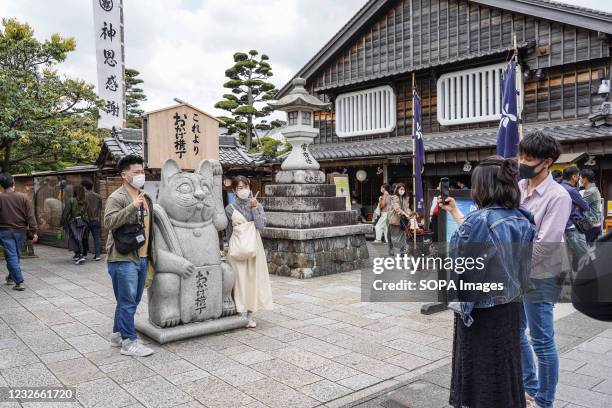 Tourists wearing face masks pose for a photo on a tourist street near Ise Jingu Shrine during the Golden Week holidays. Japan's Prefectural leaders...