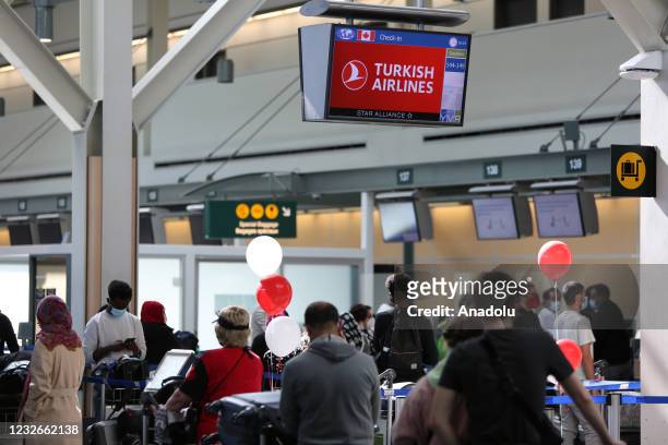Passengers wearing protective face masks wait to check in and drop off their luggages at Turkish Airlines counters before their flights to Istanbul,...