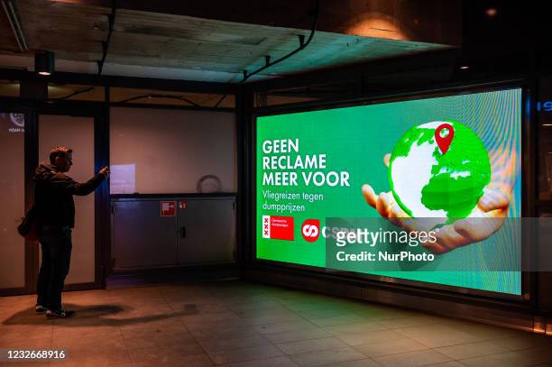 Man from the climate organization 'Reclame Fossielvrij' is taking a photo of a screen advertising display showing the end of fossil products...