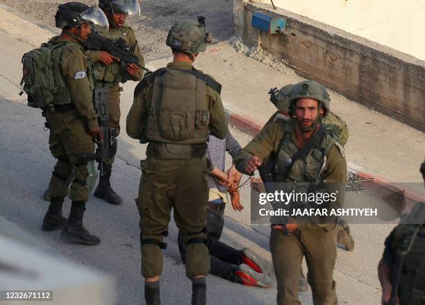 Israeli soldiers arrest a man during a security operation in the Palestinian village of Aqraba, east of Nablus in the occupied-West Bank, on May 3,...
